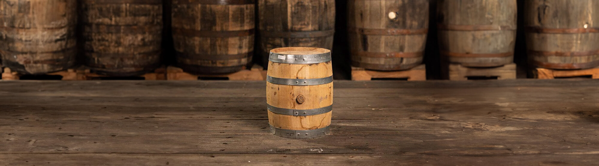 Freshly emptied 5 gallon barrel with full-size barrels behind on pallets