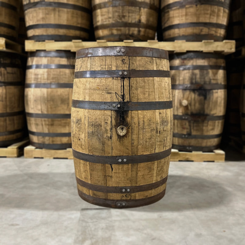 Headbung side of a Russell's Reserve Rye Whiskey Single Barrel with other used whiskey barrels on pallets in the background