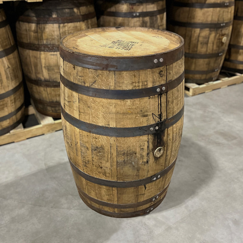 Head and headbung side of a Russell's Reserve Rye Whiskey Barrel with other used whiskey barrels in the background