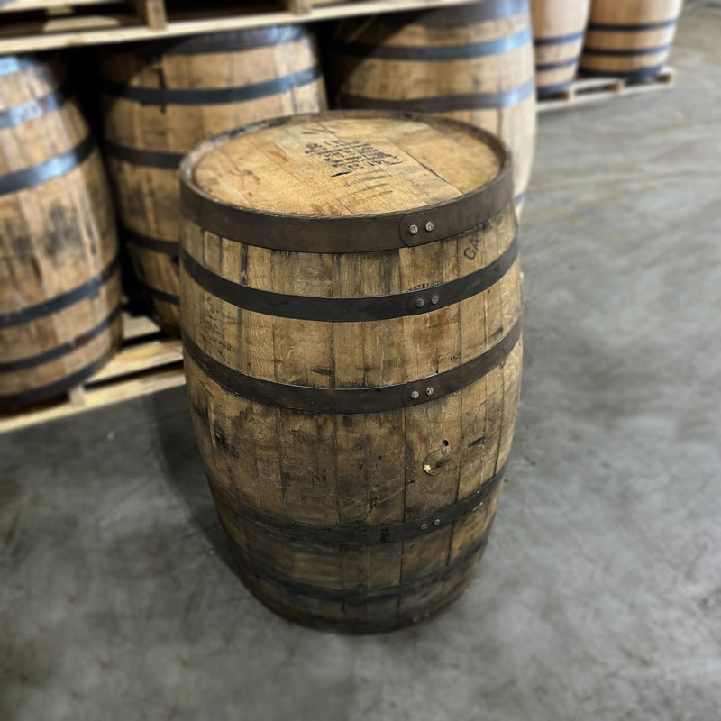 Side and head of an 8+ Year Jim Beam Black Extra Aged Bourbon Barrel with other used bourbon barrels in the background