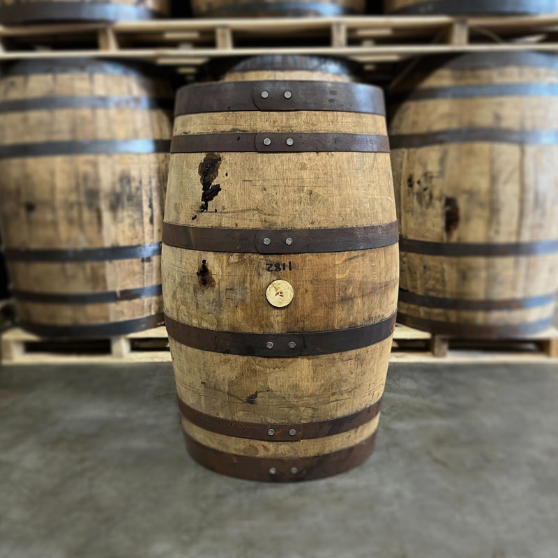 Side of a 30 Gallon Bissell Maple Syrup Barrel Ex-Bourbon with other used barrels on pallets in the background