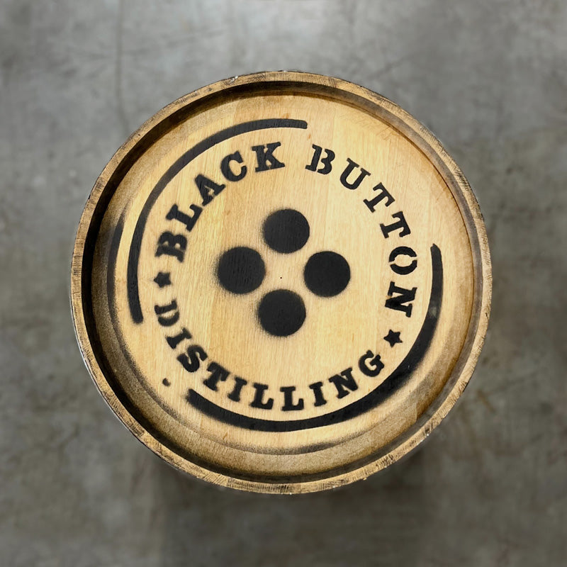 Head of a 30 Gallon Bissell Maple Syrup Ex-Bourbon Barrel with Black Button Distilling name and logo spray painted on the head