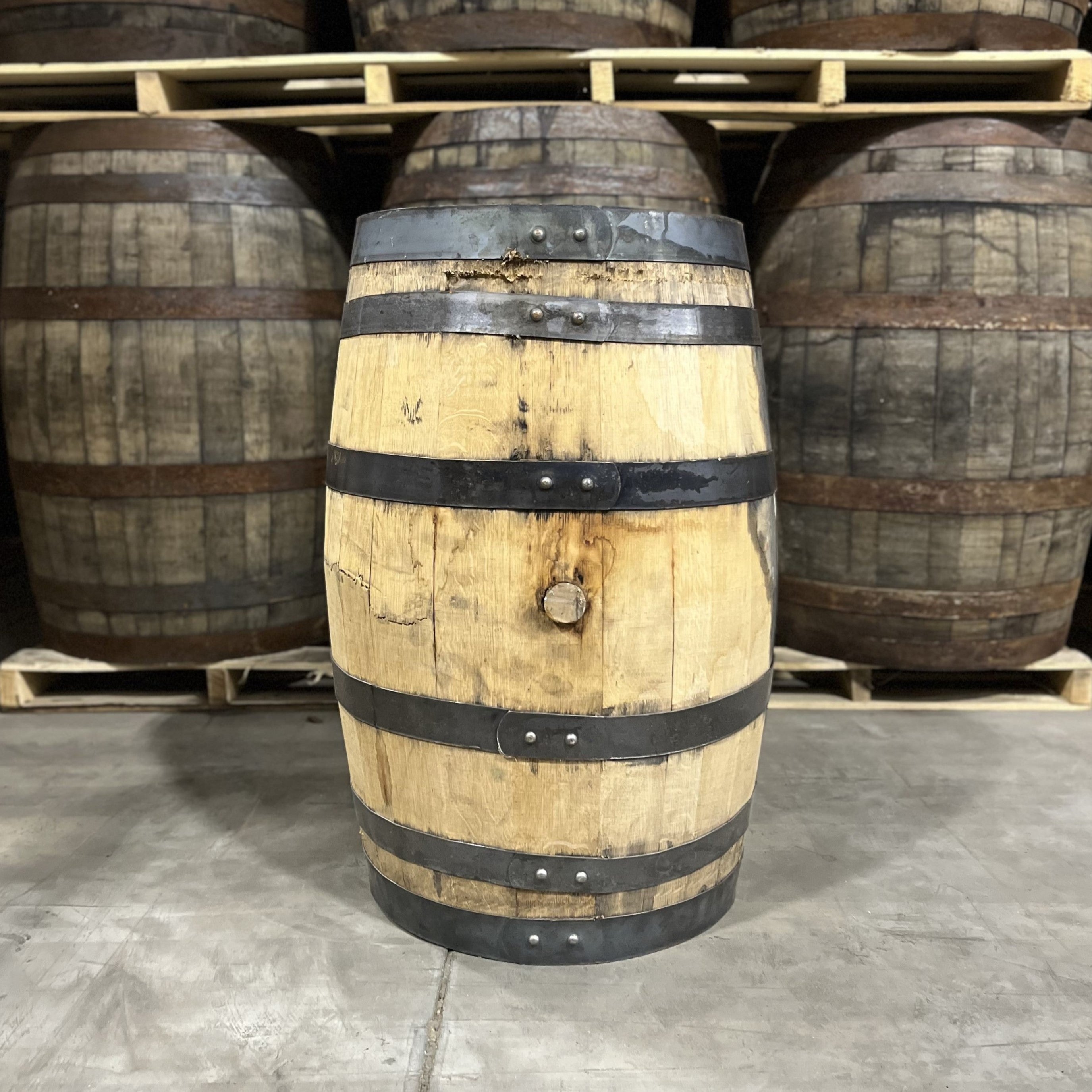 Bunghole side of a 25 Gallon Furniture Grade Whiskey Barrel with other used barrels for sale in the background