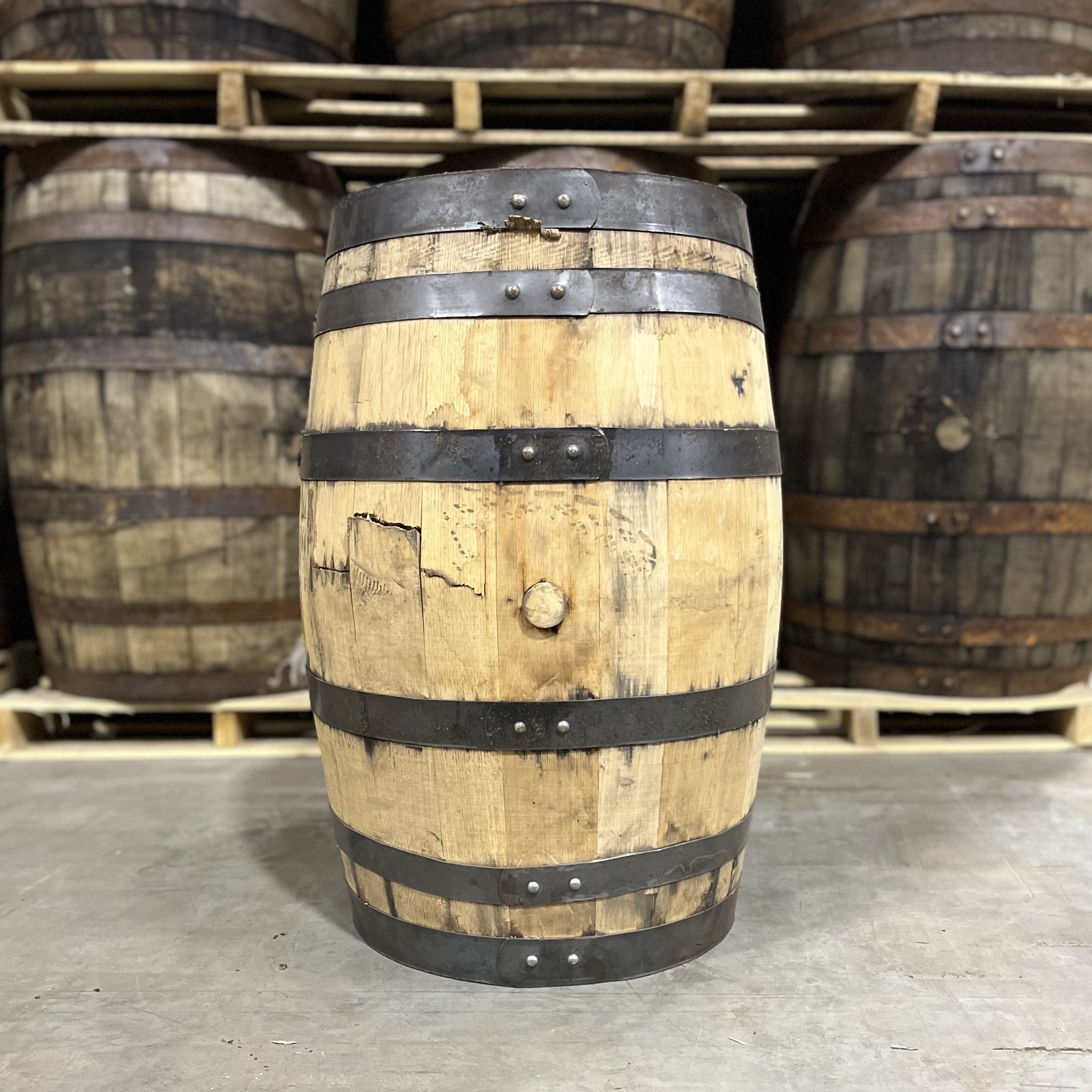 Bunghole side of a 25 Gallon Furniture Grade Whiskey Barrel with other used barrels for sale in the background