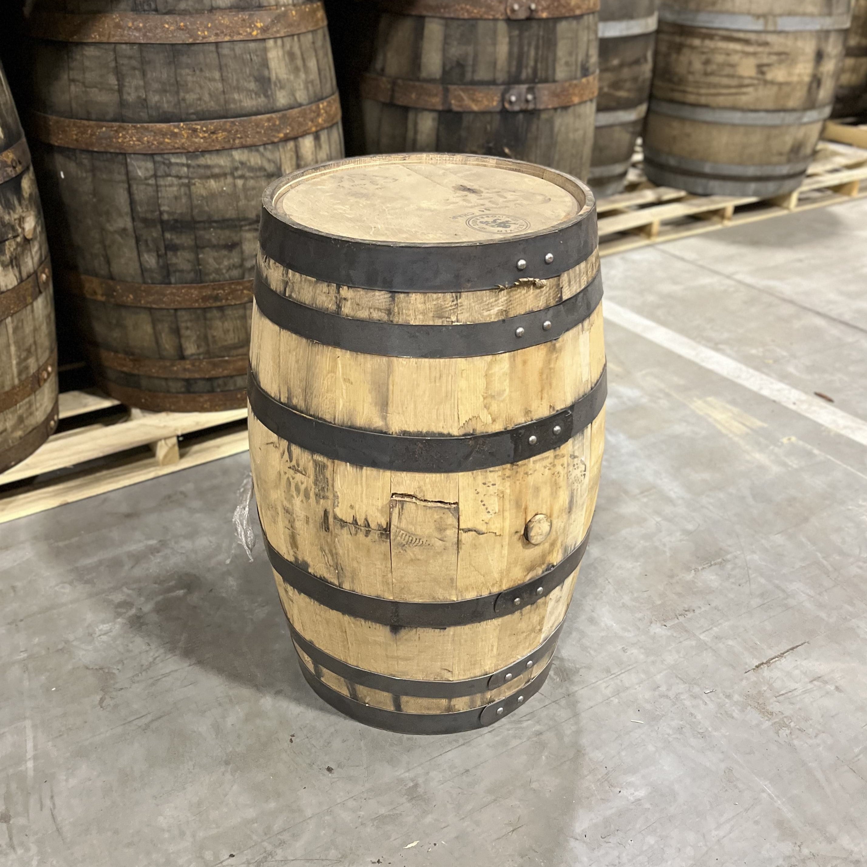 Head and Bunghole side of a 25 Gallon Furniture Grade Whiskey Barrel with other used barrels for sale in the background