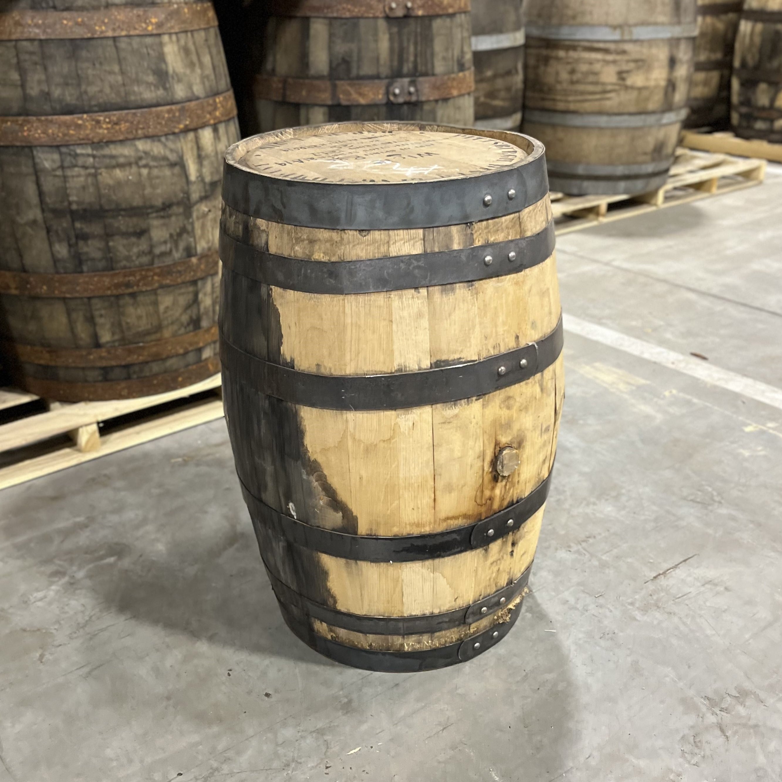 Head and Bunghole side of a 25 Gallon Furniture Grade Whiskey Barrel with other used barrels for sale in the background
