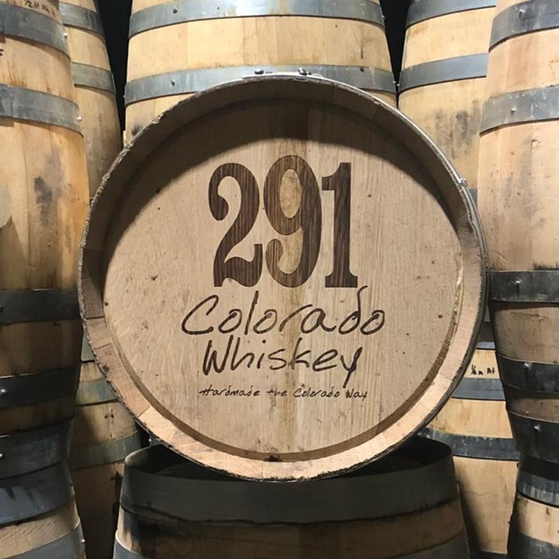 10 gallon Distillery 291 bourbon barrels stacked with one on its side with 291 Colorado Whiskey Homemade the Colorado Way engraved on head