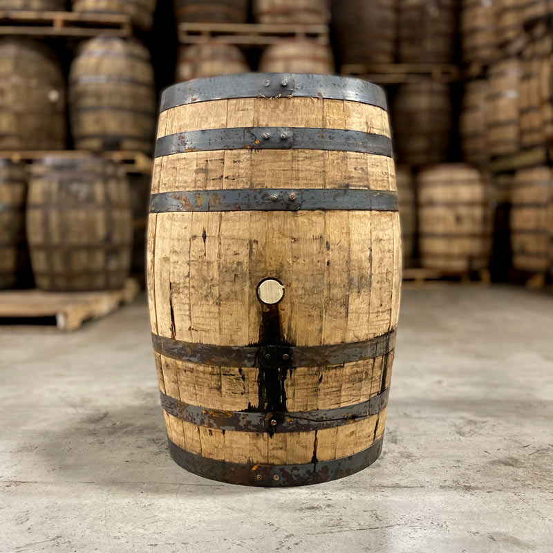 Side of a Woodford Reserve Bourbon barrel with other used bourbon barrels in the background