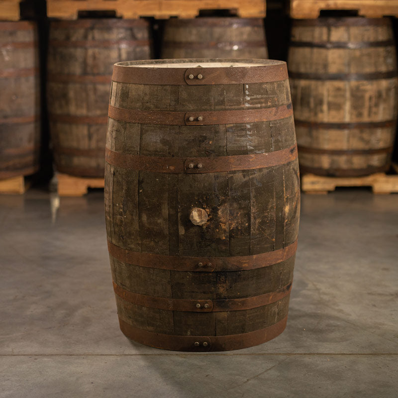 Side of a used Buffalo Trace Mash 1 Bourbon Barrel with other barrels stacked on pallets in the background