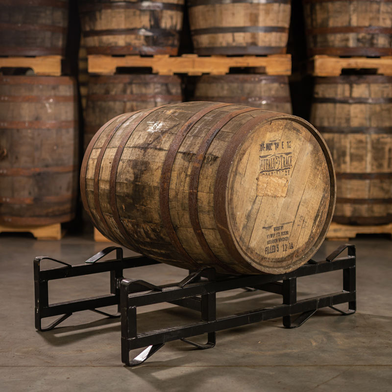 A used Buffalo Trace Mash 1 Bourbon Barrel with distillery logo and information stamped on the head and other barrels stacked on pallets in the background