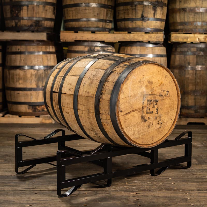 Old Forester Bourbon barrel on rack with barrels stacked on pallets in the background