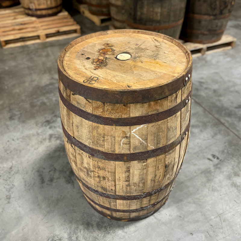 View of side and head of Templeton Rye Whiskey Barrel and barrels on pallets in the background