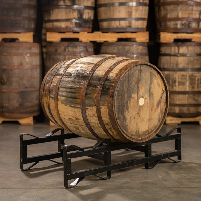 Templeton Rye Whiskey Barrel with head bung on a barrel rack with barrels stacked on pallets in the background