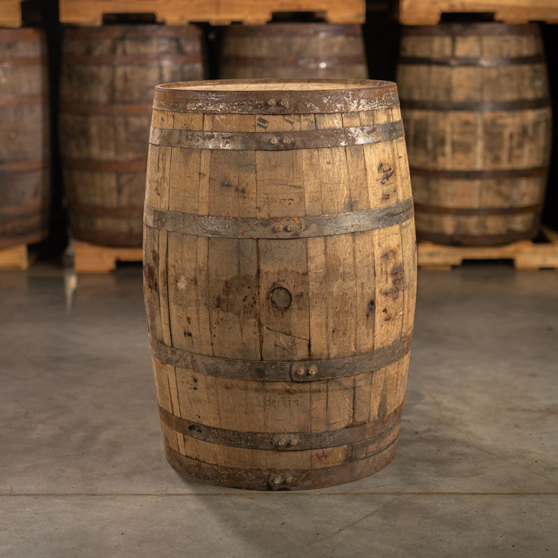 Side of a J Rieger & Co Corn Whiskey barrel with belly bung with other barrels stacked on pallets in the background