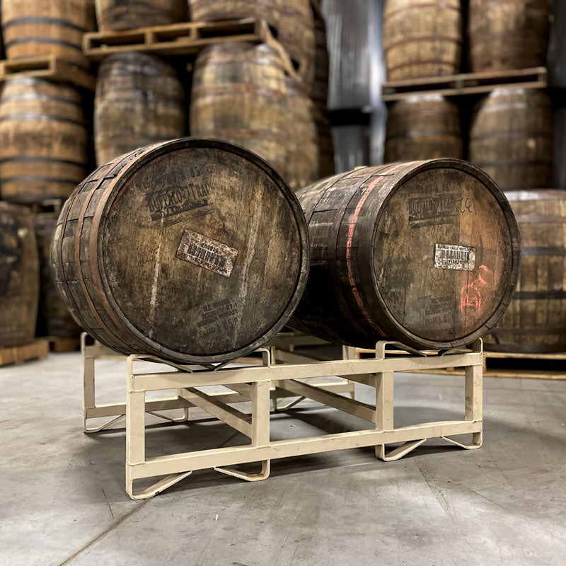 Two 15-Year Pappy Van Winkle Bourbon barrels on a rank with barrels stacked on pallets in the background