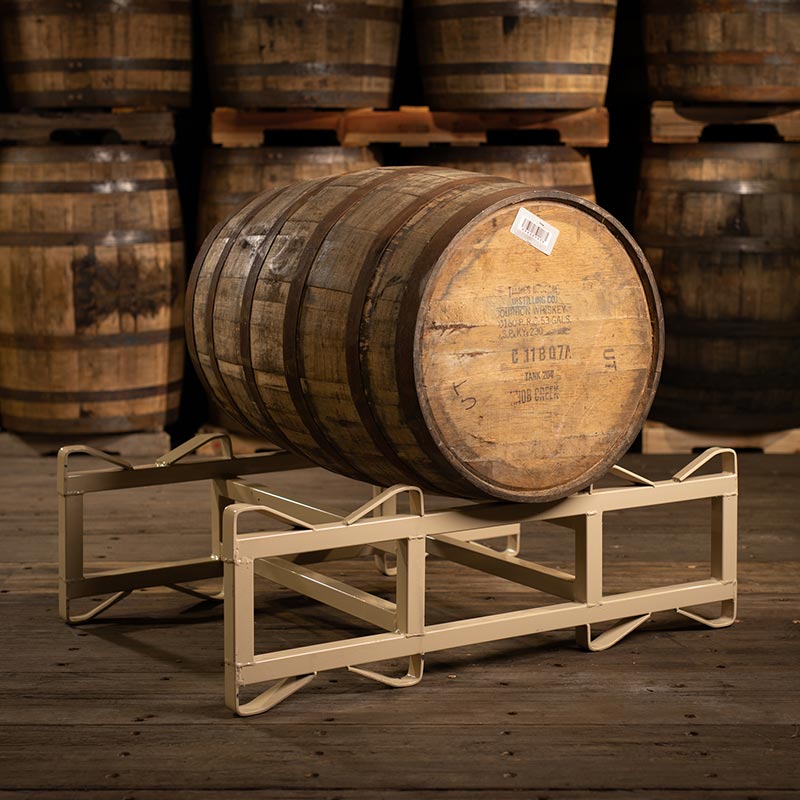 A Knob Creek Bourbon barrel on a rack with barrels stacked on pallets in the background