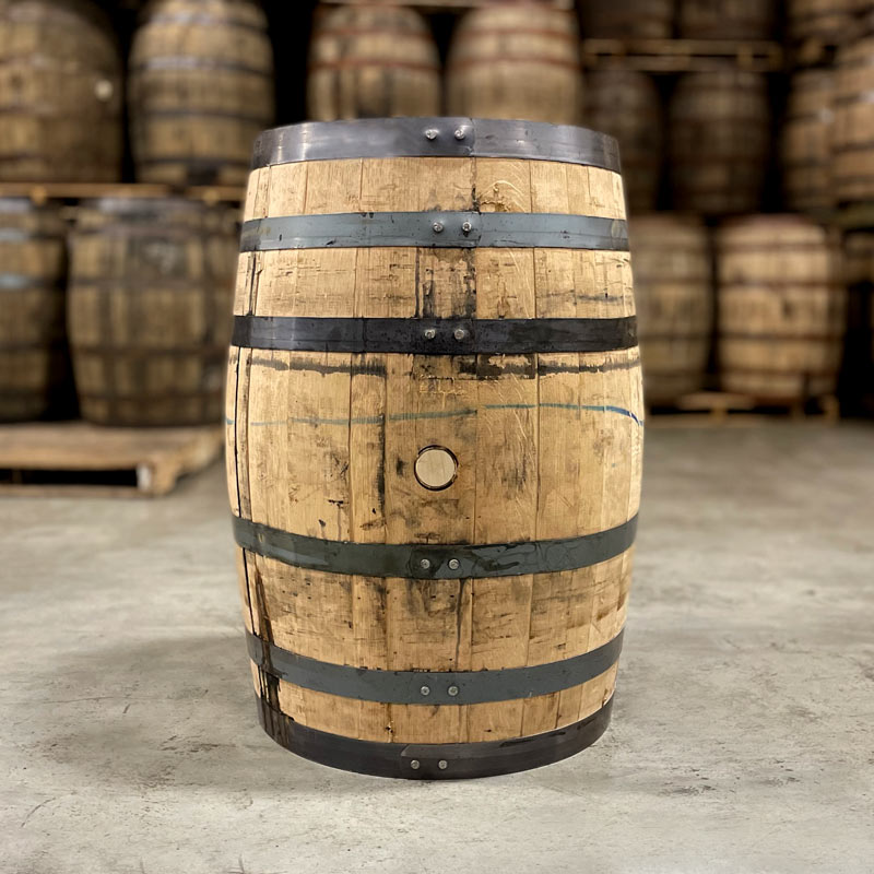 Side of a Woodford Reserve Double Oaked Bourbon barrel with other used bourbon barrels stacked on pallets in the background