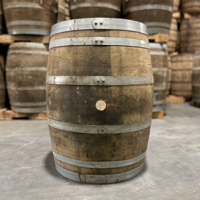 Side of a Jim Beam Wine Cask Finished Bourbon Barrel with other used wine barrels stacked on pallets in the background