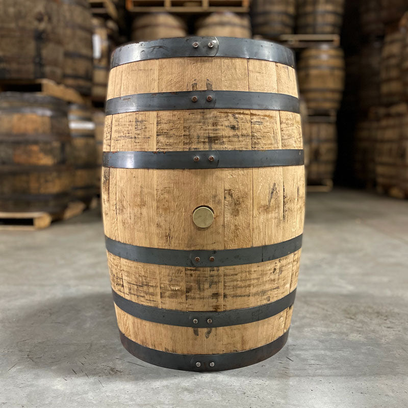 Side of a 2-Year Wild Turkey Bourbon Barrel with other used bourbon barrels stacked on pallets in the background