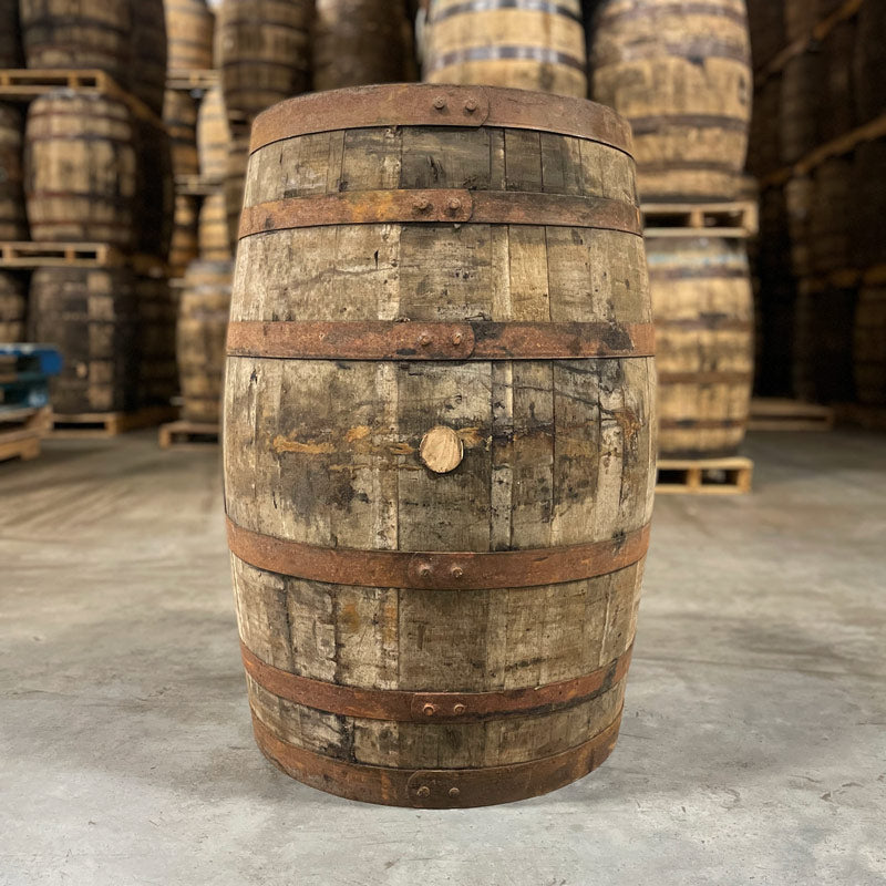 Side of an 18 Year Knob Creek Limited Edition Bourbon Barrel with other used bourbon barrels stacked on pallets in the background