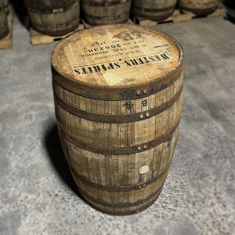 Head and side of a Western Spirits Bourbon Barrel with other used bourbon barrels in the background