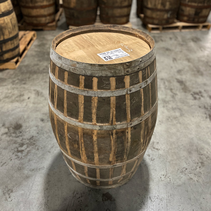 Head and side with bung of an Old Elk Cognac Finished Bourbon Barrel with other used barrels in the background