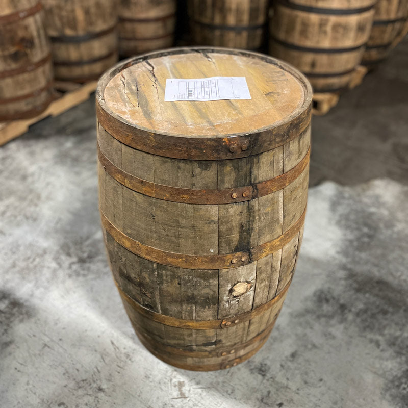 Side with bung and head of a 15 Year Widow Jane Bourbon Barrel with other used barrels on pallets in the background