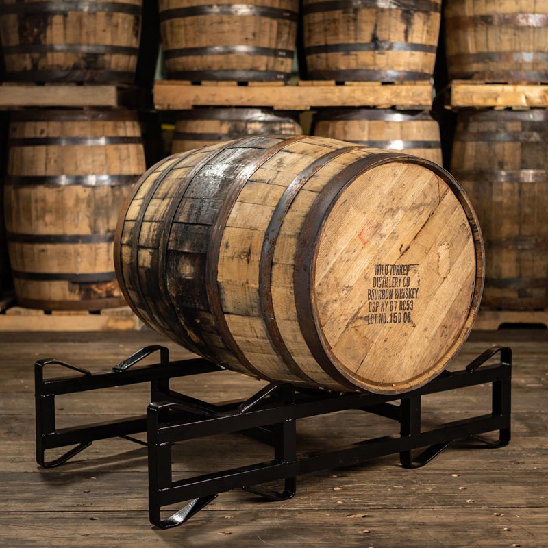 4 year age statement Wild Turkey bourbon barrel on a rack with distillery markings on head and barrels stacked on pallets in the background