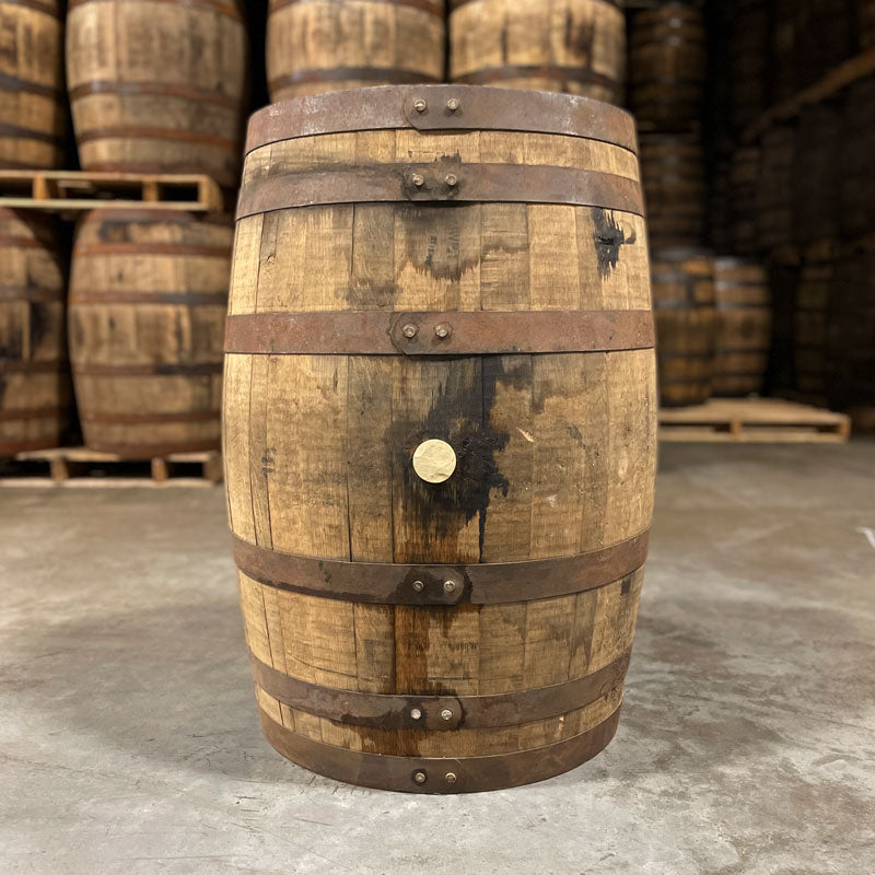 Side of a Laird's Apple Brandy Barrel with used whiskey barrels stacked on pallets in the back