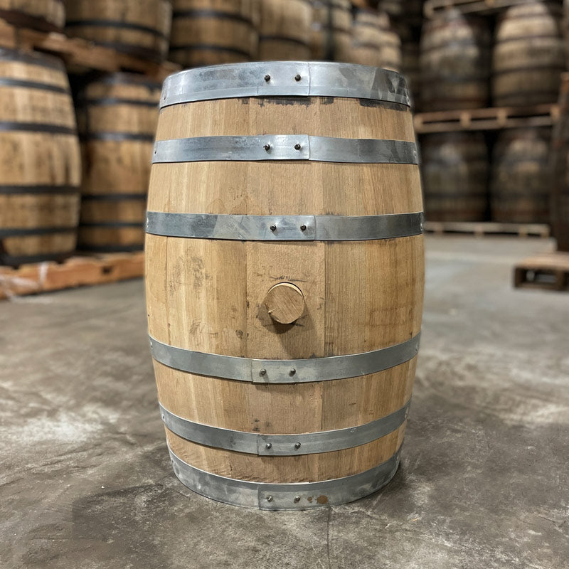 Side with bung of a 15 Gallon Lonely Oak Bourbon Barrel with other used barrels in the background on pallets