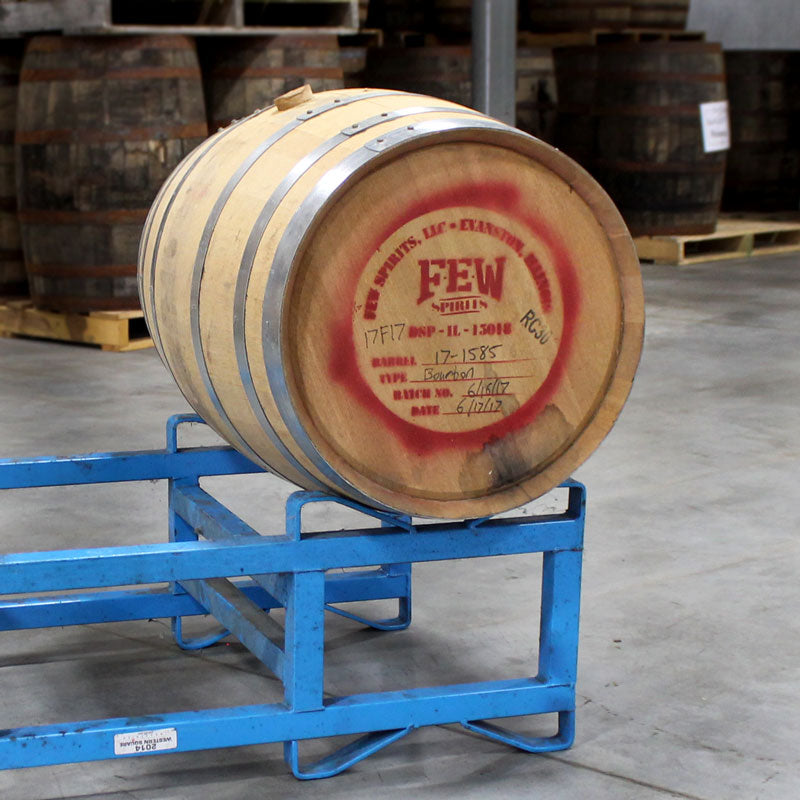30 gallon FEW Spirits Bourbon barrel with distillery logo and markings on head sitting on a barrel rack