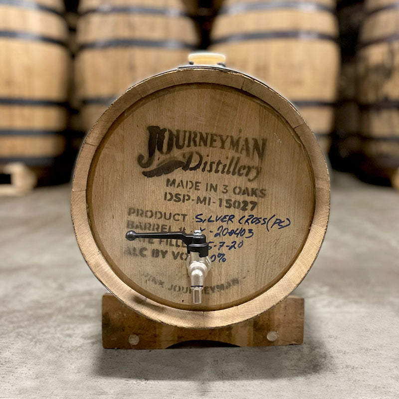 Head of a 5 Gallon Journeyman Whiskey Barrel with spigot on a stand and distillery information stamped on the head.
