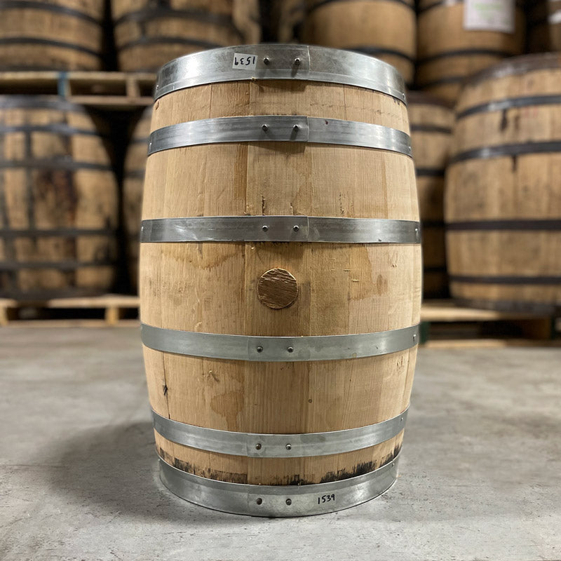 Side with bung of a 15 Gallon Old Sugar Distillery Rum Barrel with other used barrels in the background