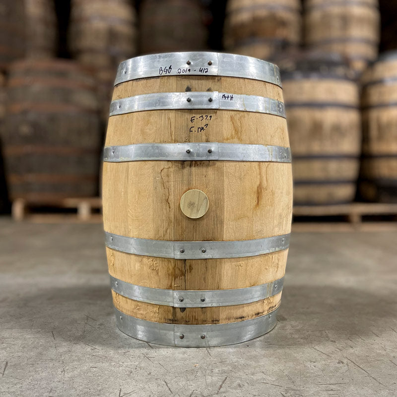Side of a 10 Gallon Distillery 291 Bad Guy Bourbon Barrel with other used barrels on pallets in the background
