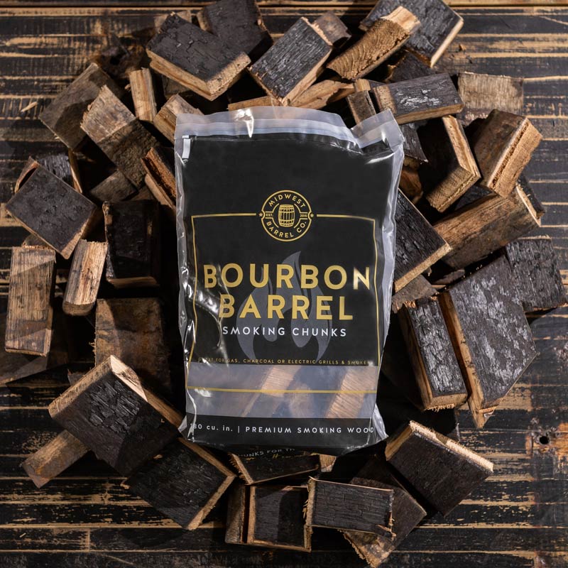 A bag full of Bourbon Barrel BBQ Smoking Wood Chunks on top of a pile of charred bourbon barrel smoking wood chunks