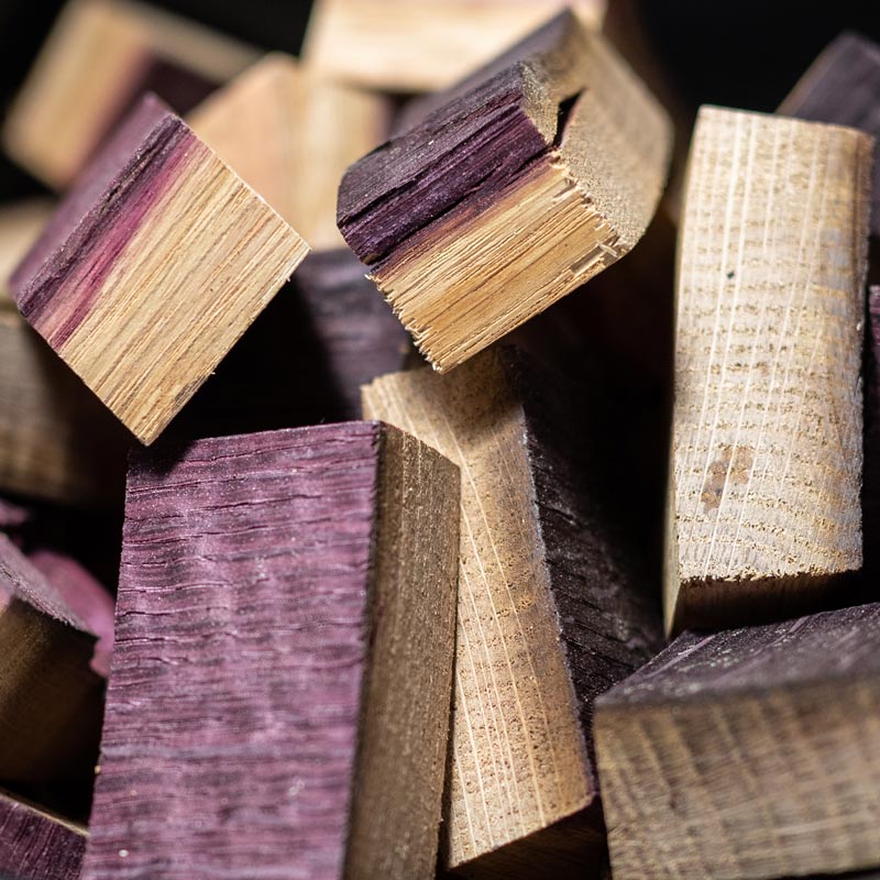 Close up view of red stained red wine smoking wood chunks