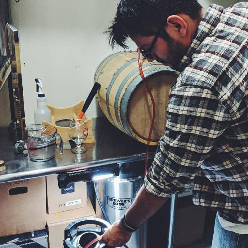 Ricky Cervantes transferring beer from a small barrel