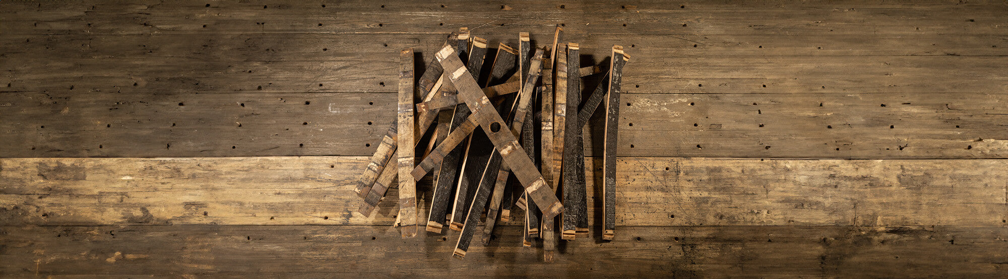 Pile of staves from a whiskey barrel with bunghole stave on top