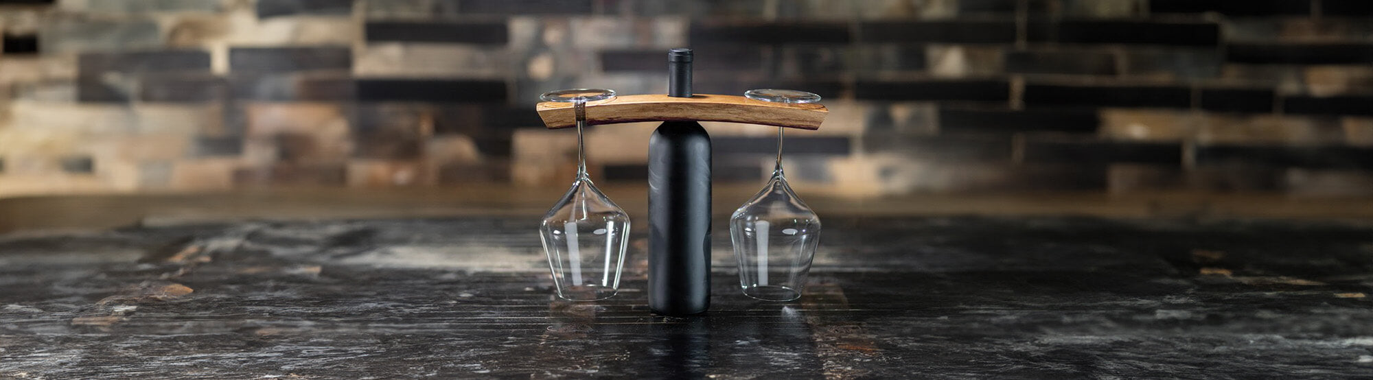 Wine caddy on a wine bottle holding two wine glasses made from wine barrel stave