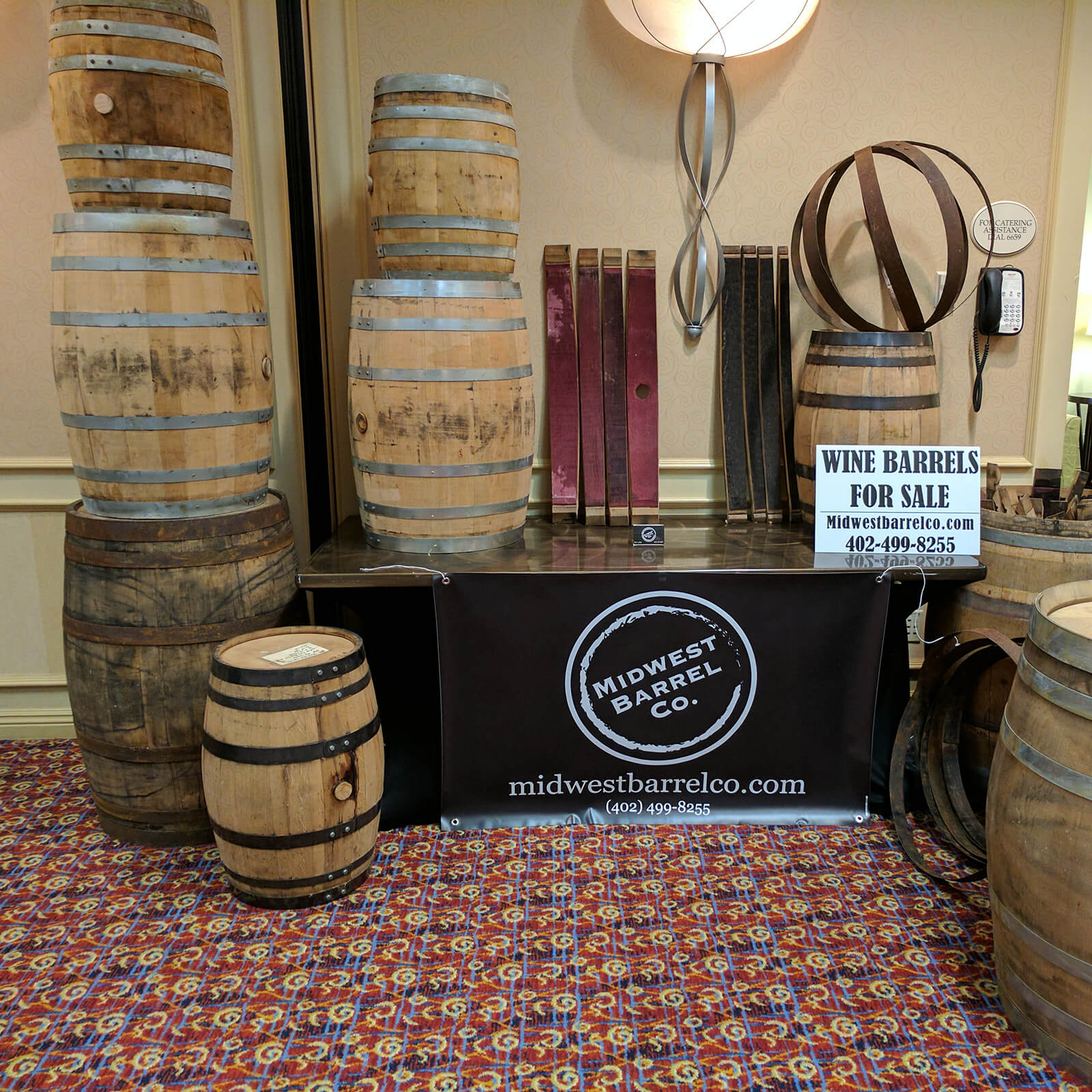 Midwest Barrel Co. display booth with different sizes of wine and whiskey barrels, barrel staves and barrel rings with sign that says Wine Barrels For Sale