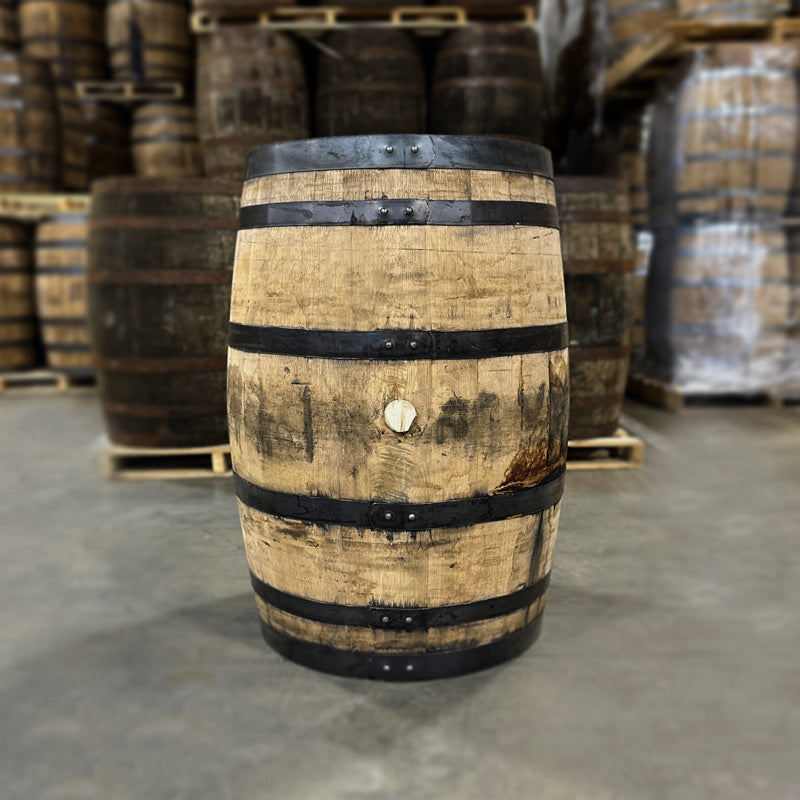 Bunghole side of a Penelope Toasted Bourbon Barrel with other used barrels stacked in the background