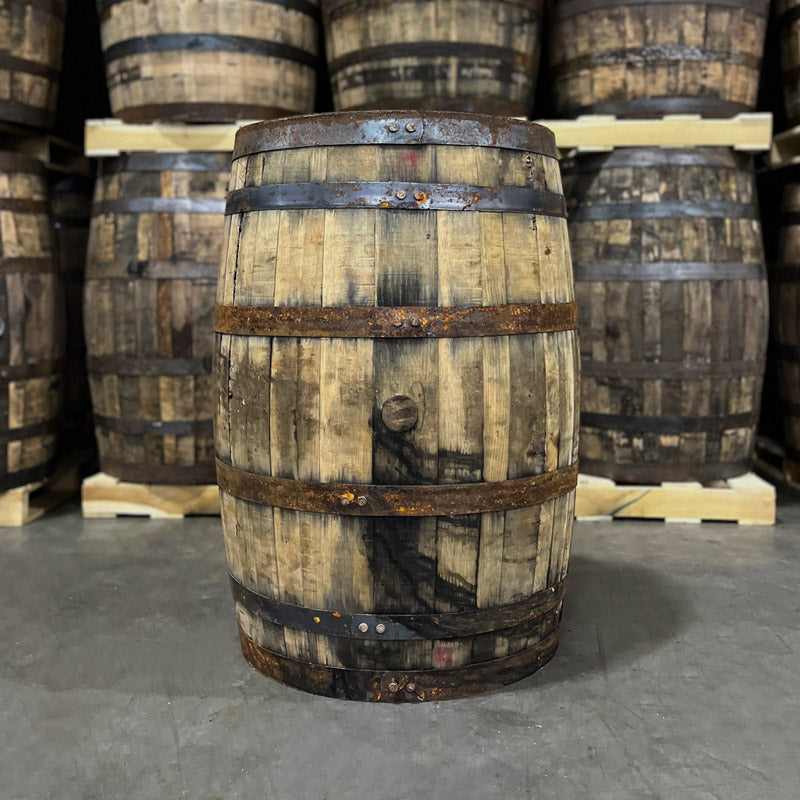 Bunghole side of a Russell's Reserve Bourbon Single Barrel with other used bourbon barrels on pallets in the background