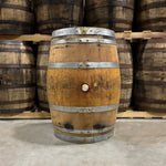 Bunghole side of a Bardstown Bourbon Co. Wine Cask Finished Bourbon Barrel Fresh Dumped with other used bourbon barrels stacked on pallets in the background