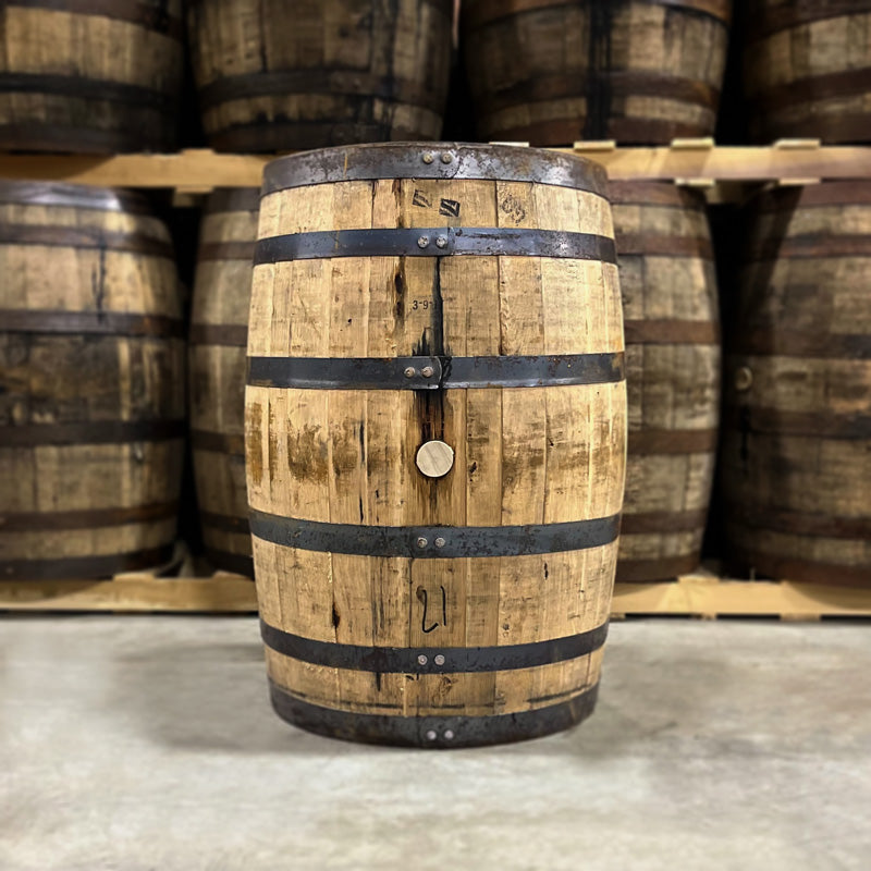 Side with bung of a 6 Year Austin Nichols Wild Turkey Bourbon Barrel with other used bourbon barrels stacked on pallets in the background