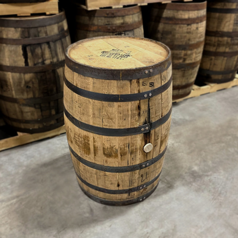 Head and side of a 6 Year Austin Nichols Wild Turkey Bourbon Barrel with other used bourbon barrels stacked on pallets in the background