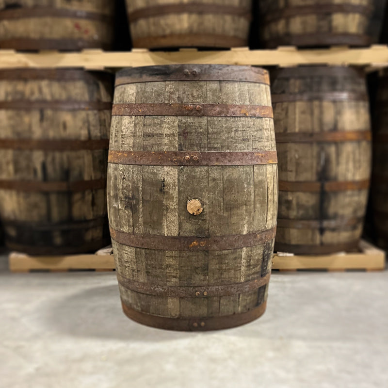 Bunghole side of a 4 Year Wild Turkey Rye Whiskey Barrel with other used whiskey barrels stacked on pallets in the background