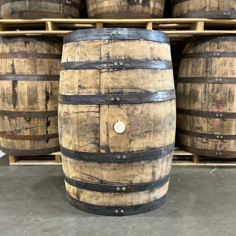 
                  
                    Bunghole side of a Wilderness Trail Wheated Bourbon Barrel with other used bourbon barrels for sale in the background on pallets
                  
                
