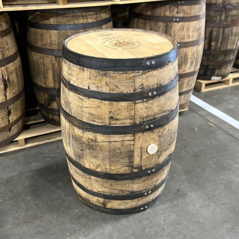 Head and side of a Wilderness Trail Wheated Bourbon Barrel with other used barrels in the background