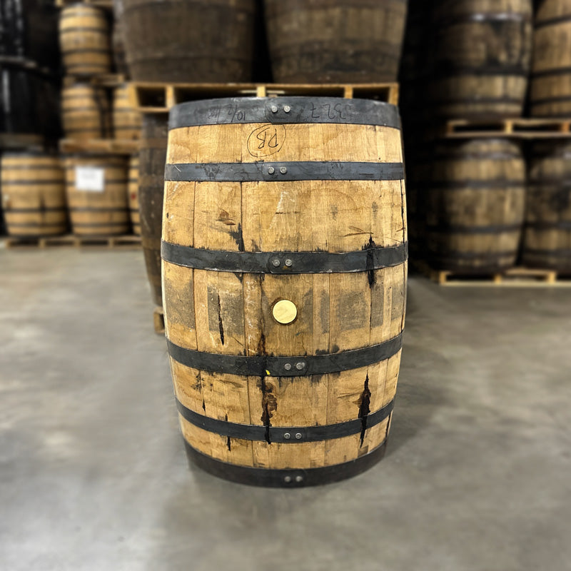 Bunghole side of a Kings County Peated Bourbon Barrel with other used bourbon barrels stacked in the background