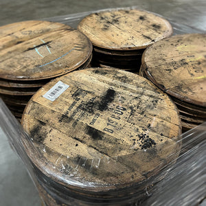 
                  
                    A pallet of bourbon and whiskey barrel heads with distillery stamps wrapped in plastic wrap
                  
                